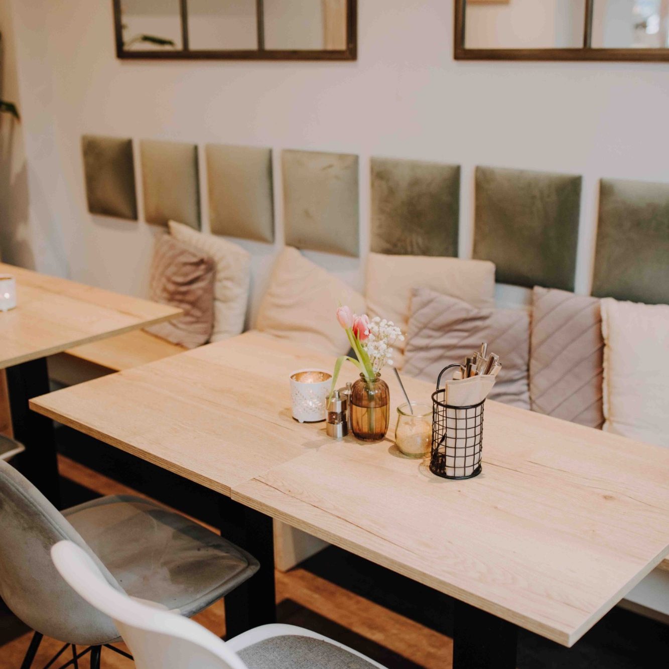 Gemütlicher Innenraum des Café Palena mit Holzdesign, gemütlichen Kissen und Pflanzen.
